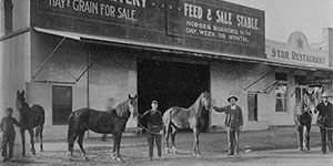 An old photo of Clovis Livery and Feed shop with men and horses in front